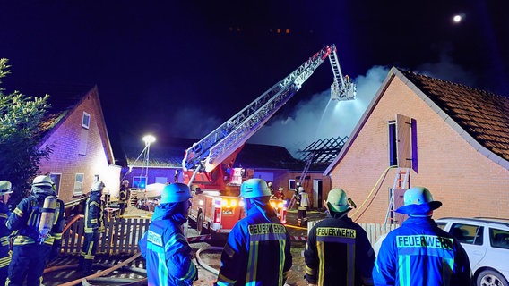 Einsatzkräfte der Feuerwehr stehen vor einem brennenden Stallgebäude. © Nord-West-Media TV 