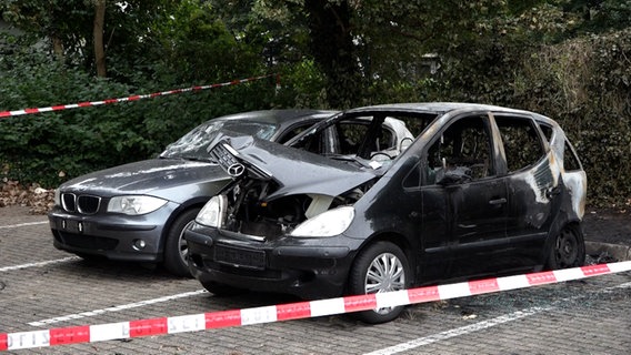 Zwei ausgebrannte Autos stehen auf einem Parkplatz. © Nord-West-Media TV 