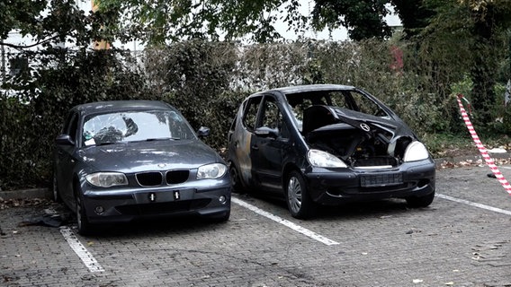 Zwei ausgebrannte Autos stehen auf einem Parkplatz. © Nord-West-Media TV 