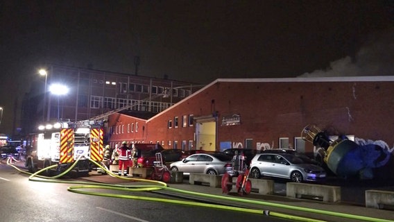 Feuerwehrleute stehen vor einer brennenden Lagerhalle in Bremen. © Nord-West-Media TV 