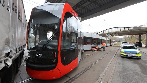 Eine Straßenbahn der BSAG in Bremen steht entgleist auf einer Straße mit Schäden, diekt daneben ein Lastwagen. Polizeifahrzeug und Arbeiter im Hintergrund. © TNN/dpa Foto: Christian Butt