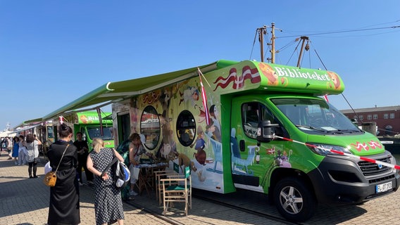 Menschen stehen beim Internationalen Fahrbibliothekskongress in Cuxhaven vor einem Bücherbus aus Dänemark. © NDR Foto: Catherine Grim