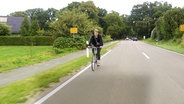 Eine Frau fährt auf dem Dorf Fahrrad. © NDR 