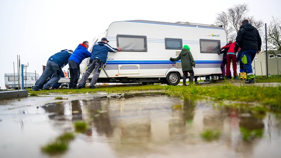 Mit gegenseitiger Unterstützung schieben Urlauber ihre Wohnwagen auf die Parzellen auf einem Campingplatz in Schillig. © dap-Bildfunk Foto: Sina Schuldt