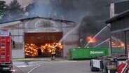 Einsatzkräfte der Feuerwehr löschen einen Brand auf einem Betriebshof. © Nord-West-Media TV 