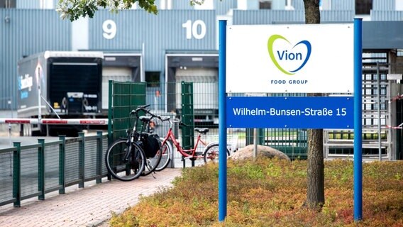 Ein Schild dem Logo des Unternehmens steht vor einer Zufahrt zu einem Schlachthof des Lebensmittelkonzerns Vion. © dpa Foto: Hauke-Christian Dittrich