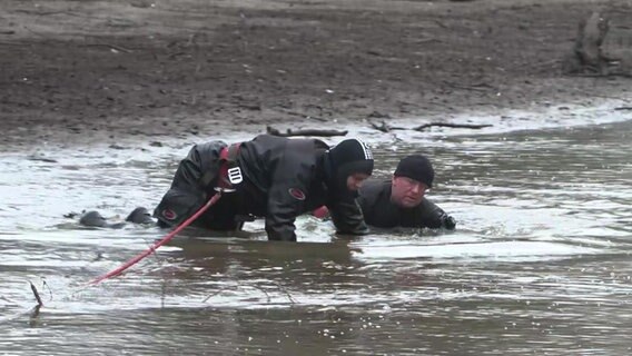 Zwei Männer suchen im Schlamm des Delmenhorsters Burggraben nach einer Waffe. © NDR 