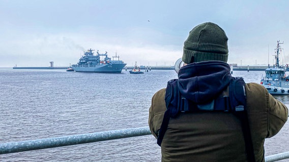 Ein Mann fotografiert den Einsatzgruppenversorger "Frankfurt am Main", während er in Wilhelmshaven einläuft. © NDR Foto: Peter Becker