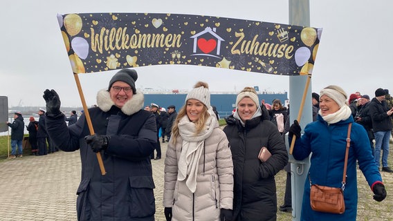 Angehörige eines Crewmitgliedes des Einsatzgruppenversorger "Frankfurt am Main" warten mit einem Transparent an der Kaje in Wilhelmshaven. © NDR Foto: Peter Becker