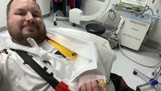 Ein Deutschland-Fan liegt mit einem gebrochenen Arm auf einer Liege in einem Krankenhaus. © privat Foto: Kai Flathmann