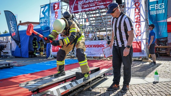 Feuerwehrmann Philipp Reumann von der Freiwilligen Feuerwehr Eckwarden schlägt bei der Firefighter Combat Challenge in Bremerhaven mit einem Hammer auf ein Gewicht. © dpa-Bildfunk Foto: Focke Strangmann