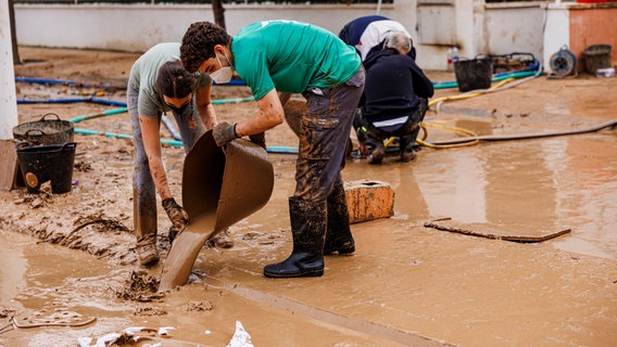 Bewohner der spanischen Provinz Valencia bei Aufräumarbeiten nach der Flut. © picture alliance 