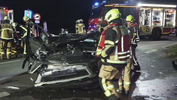 Feuerwehrleute stehen an einem demolierten Auto nach einem Unfall in Garrel. © Nord-West-Media TV 