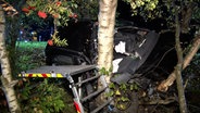 Ein Auto liegt nach einem Unfall bei Geeste verkeilt zwischen Bäumen. © Nord-West-Media TV 