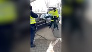 Ein Polizist versucht die Scheibe eines Autos einzutreten. © instagram.com/dvhn.nl 