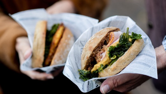 Ein Paar hält auf dem Rathausmarkt zwei Grünkohlburger in den Händen. © dpa Foto: Hauke-Christian Dittrich