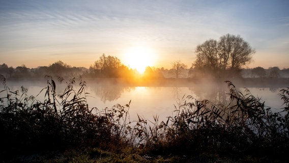 Die Sonne geht am Morgen über der Hunte am Achterdiek auf, während leichter Nebel über den Fluss zieht. © Hauke-Christian Dittrich/dpa Foto: Hauke-Christian Dittrich