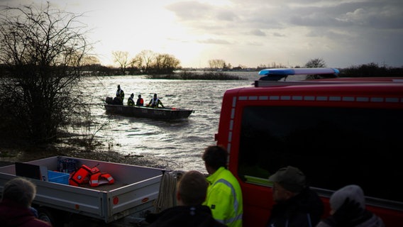 Einsatzkräfte der Feuerwehr transportieren Bewohner des Ortes Eissel mit einem Boot durch ein Hochwassergebiet. © NDR Foto: Mirco Seekamp