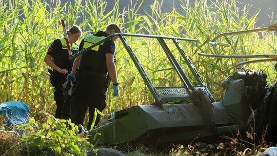 Polizisten untersuchen nach einem Unfall einen Häcksler in einem Maisfeld in Hülseberg © Nord-West-Media TV 