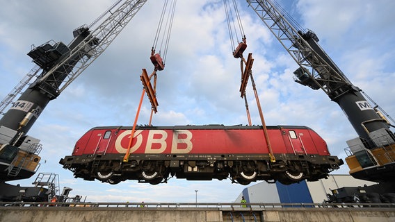 Eine E-Lok von Rail Cargo Carrier Germany (RCC) wird mit einem Kran auf das Binnenschiff "Rolf-Hein" gehoben und auf dem Seeweg nach Bremen transportiert. © dpa Foto: Lars Penning