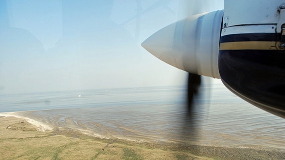 Ein Blick aus einem Inselflieger auf die Insel Juist und die Nordsee. Die Rotorblätter drehen sich. © NDR Foto: Stefanie Riepe