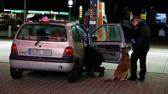 Polizeibeamte durchsuchen zusammen mit einem Spürhund einen Pkw. © Nord-West-Media TV 