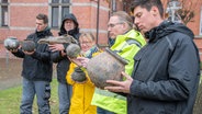 Viacheslav Hladkyi, Johann Arends, Claudia Neutzer, Dr. Jan F. Kegler und Taras Khromushyn zeigen die ungewöhnlich gut erhaltenen Kugeltöpfe aus dem Spätmittelalter und einen Pferdeschädel, die bei den Grabungen auf der Japaninsel gefunden wurden. © Ostfriesische Landschaft 