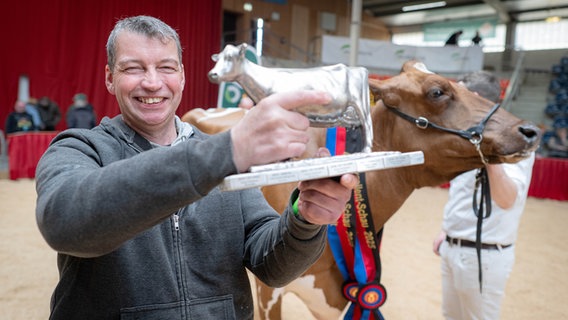 Thomas Rohdemann steht vor seiner Kuh "Helene", die den Titel "Miss Ostfriesland 2025" gewonnen hat. © dpa Foto: Sina Schuldt