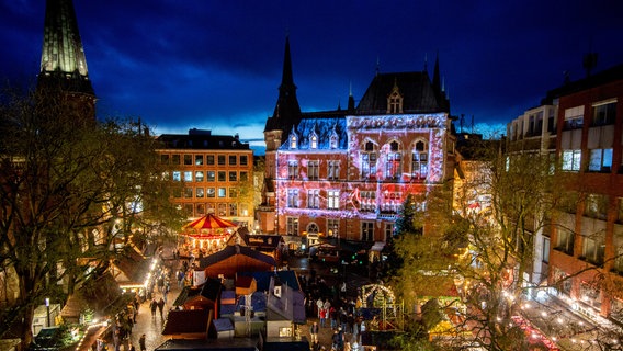 Oldenburg: Besucher gehen über den Lamberti-Markt in der Innenstadt, während das Rathaus mit einer Animation illuminiert wird. © dpa-Bildfunk Foto: Hauke-Christian Dittrich