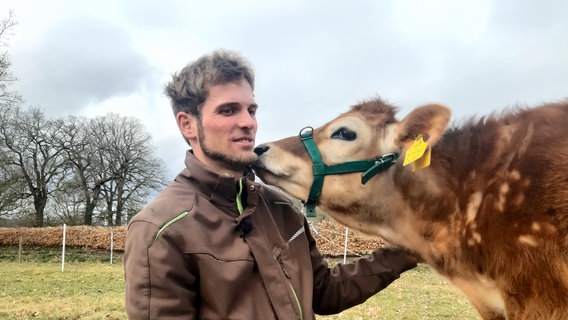 Der blinde Landwirt Axel Duensing mit einem Jersey-Kälbchen auf der Weide. © NDR Foto: Lotti Höfer