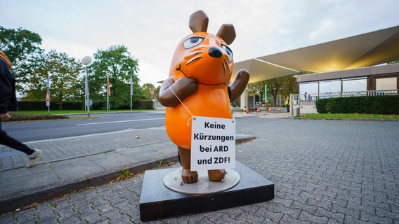 Die Maus aus der "Sendung mit der Maus" steht im Zugangsbereich zum ZDF und fordert auf einem Schild "Keine Kürzungen bei ARD und ZDF!". © picture alliance/dpa Foto: Andreas Arnold