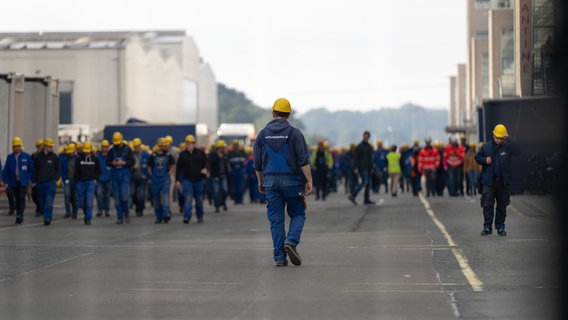 Mitarbeiter der Meyer Werft laufen nach einer Betriebsversammlung Papenburg über das Firmengelände © dpa Foto: Izabella Mittwollen