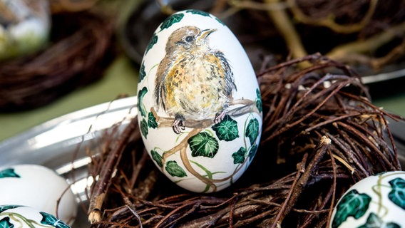 Eier mit dem Motiv einer Drossel liegen in einem Nest auf einem Tisch. © dpa-Bildfunk Foto: Hauke-Christian Dittrich