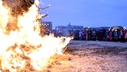 Menschen stehen um ein großes Osterfeuer in Norddeich herum. © TeleNewsNetwork 