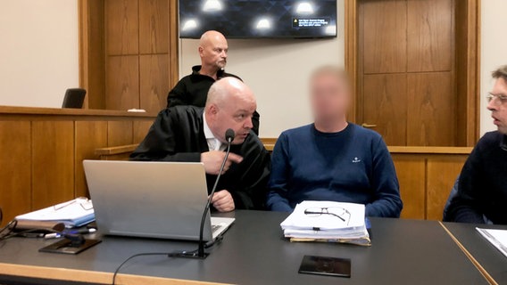 Ein wegen mutmaßlichen Drogenhandels Angeklagter sitzt neben seinem Rechtsanwalt Frank Butzelar (l.) und einem Dolmetscher im Saal des Landgerichts Oldenburg. © picture alliance/dpa Foto: Lennart Stock