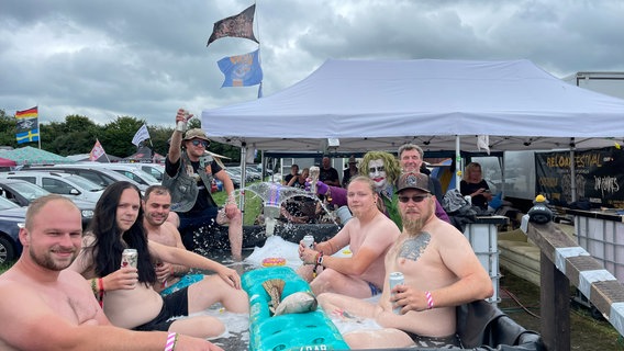 Eine Gruppe Besucher des "Reload" Festival sitzen in einem Pool auf dem Festivalgelände in Sulingen. © NDR Foto: Andreas Gervelmeyer