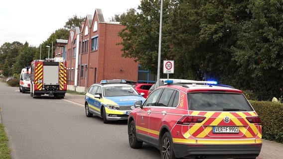 Vor einer Grundschule in Riede stehen ein Polizeiauto, Rettungswagen, Notarzt und ein Feuerwehrauto. © Nordwestmedia 