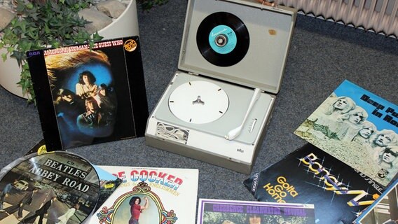 A collection of vinyl records and an old record player from the 1970s on a carpet.  © NDR Photo: Claus Halstrup