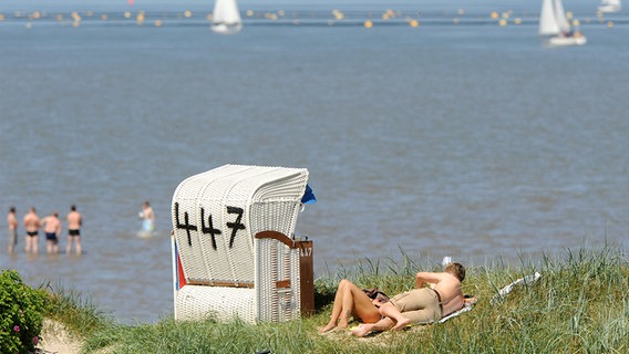 Urlauber liegen an einem Strand mit Strandkorb. © dpa-Bildfunk Foto: Ingo Wagner