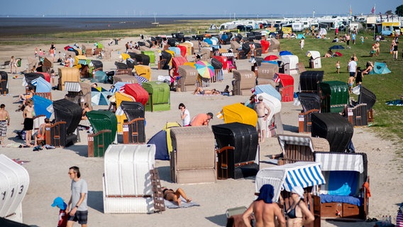 Zahlreiche Touristen sitzen bei sommerlichen Temperaturen in bunten Strandkörben am Strand von Dangast. © dpa Foto: Hauke-Christian Dittrich