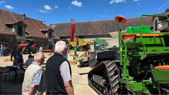 Menschen besuchen beim Tag des offenen Hofes die Burg Warberg und betrachten die ausgestellten Landmaschinen. © NDR Foto: Marie Stiller