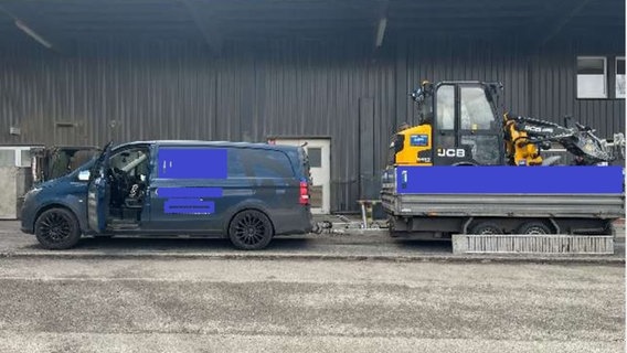 Ein dunkelblauer Transporter mit einem Anhänger, der mit einem Radlader beladen ist. © Polizeiinspektion Cuxhaven Foto: Polizeiinspektion Cuxhaven