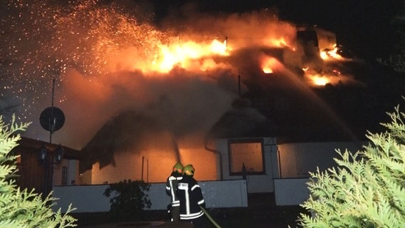 Einstzkräfte der Feuerwehr vor einem brennenden Reetdachhaus in Varel. © NonstopNews 