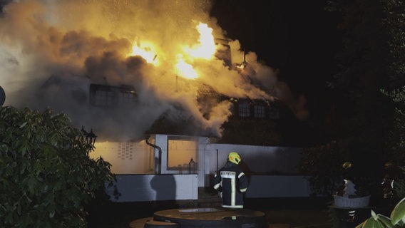 Einstzkräfte der Feuerwehr vor einem brennenden Reetdachhaus in Varel. © NonstopNews 