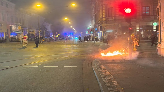 Ein Feuerwehrmann steht auf der Sielwall-Kreuzung in Bremen und löscht einen brennenden Gegenstand auf der Straße. Weitere Einsatzkräfte im Umfeld. © NDR Foto: Janosch Lenhart