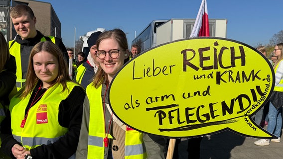 Mitglieder der Gewerkschaft ver.di halten bei einem Warnstreik oin Oldenburg ein Schild mit der Aufschrift "Lieber reich und krank als arm und pflegend!" © NDR Foto: Pascal Klug