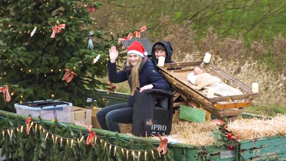 Two women on a tractor trailer decorated for Christmas.  © NonstopNews 