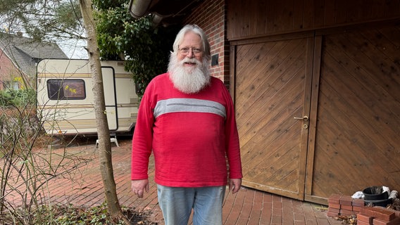 Peter Hochheiden steht mit langem Rauschebart vor Haus und Wohnwagen in Hude © Pascal Klug / NDR Foto: Pascal Klug