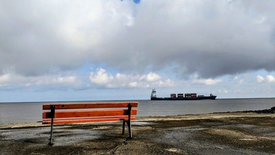 Blick auf eine Bank und ein Containerschiff bei Otterndorf. © NDR Foto: Silke Grabner