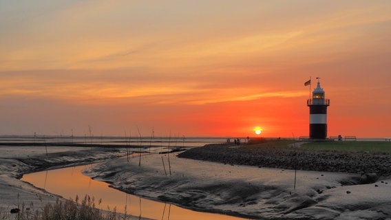 Die Sonne geht hinter einem Leuchtturm unter. © NDR Foto: Henning Predel